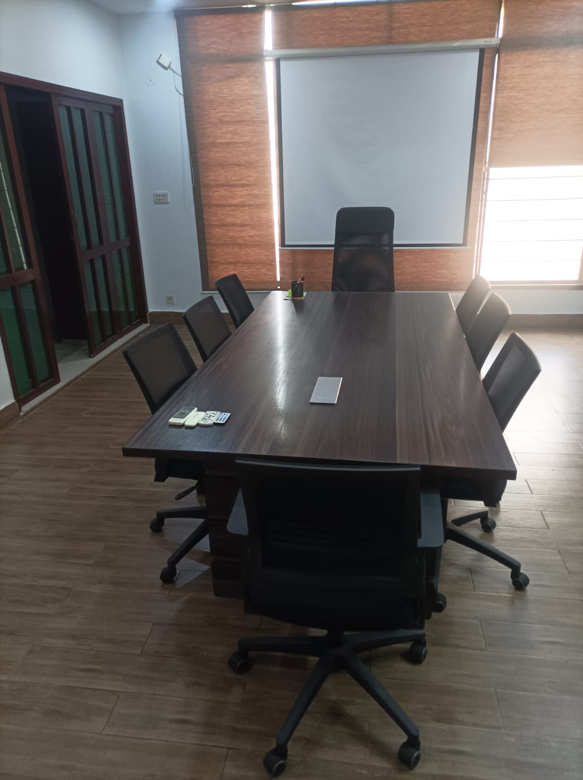 8-seat multimedia boardroom with overhead projector screen and mesh chairs at KAMH coworking space, Lahore