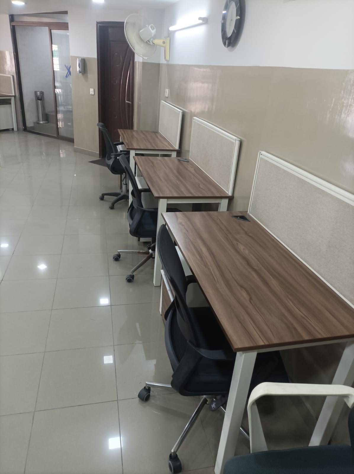 Row of walnut dedicated desks with privacy dividers at KAMH office space Lahore