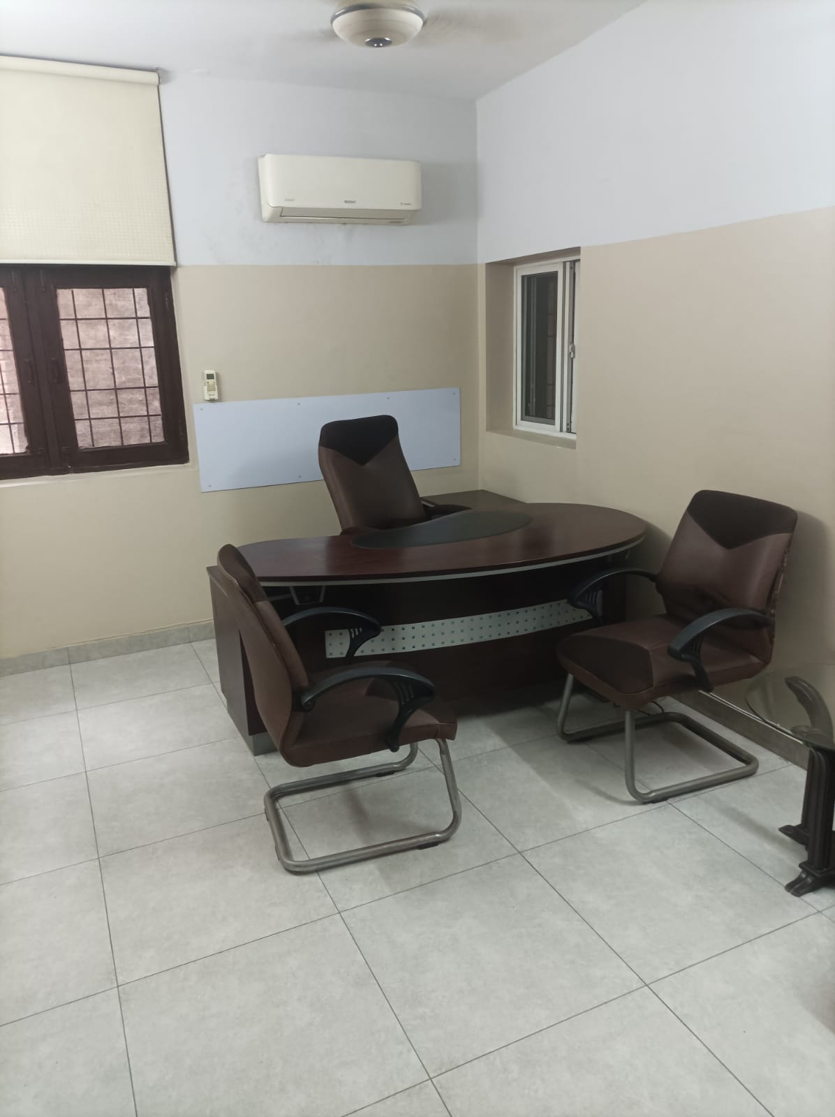 Director private cabin with curved executive desk and two brown visitor chairs at KAMH Lahore