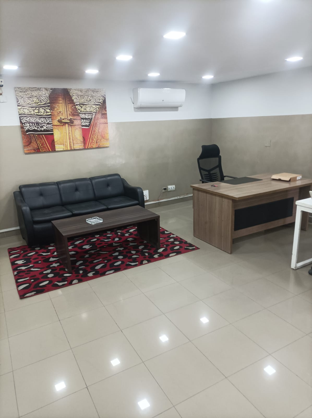 Executive suite with executive desk, black leather sofa and red rug at KAMH Lahore