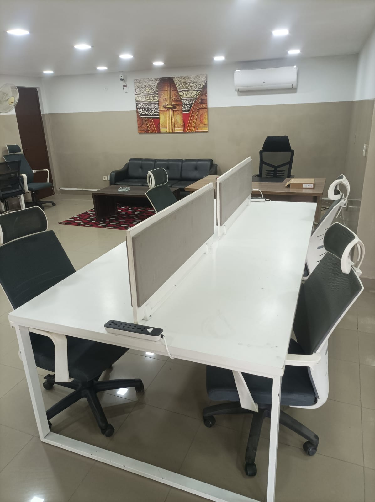 Main coworking hall with white hot desks and lounge seating at KAMH Lahore