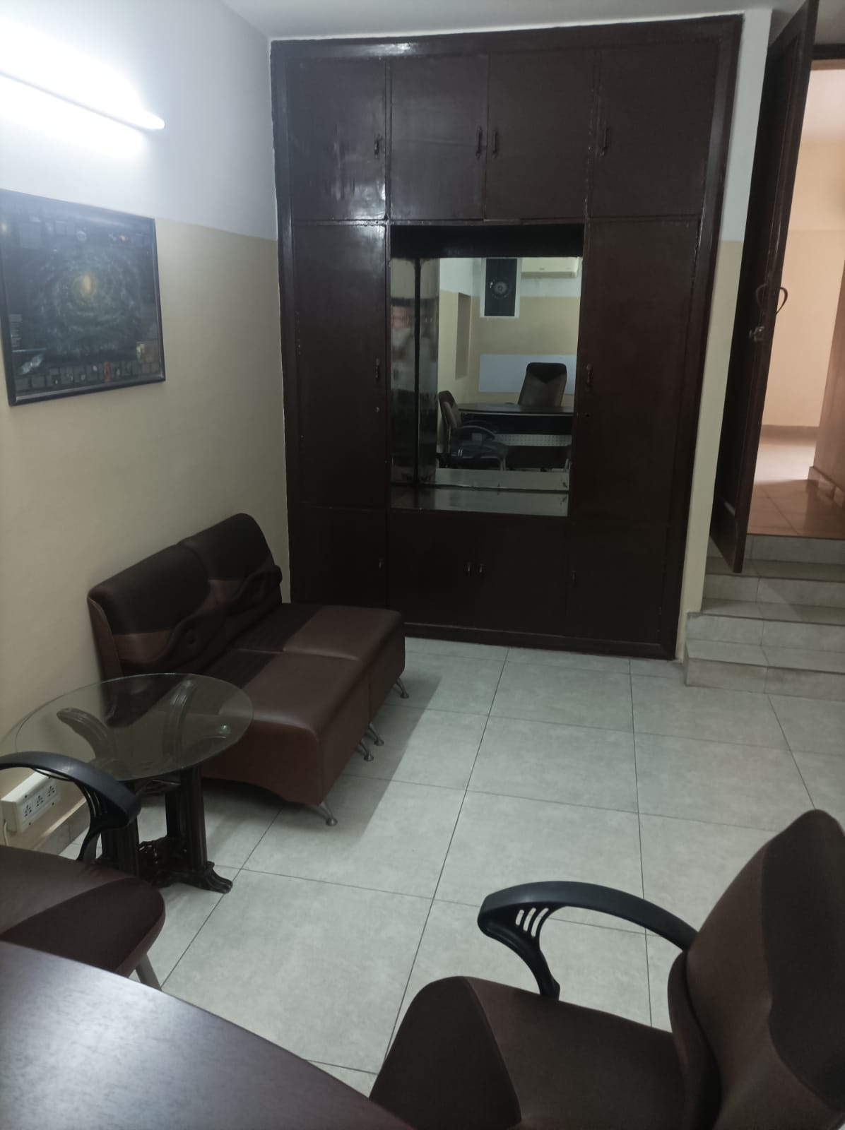 Private office waiting area with brown leather sofa and glass table at KAMH Lahore